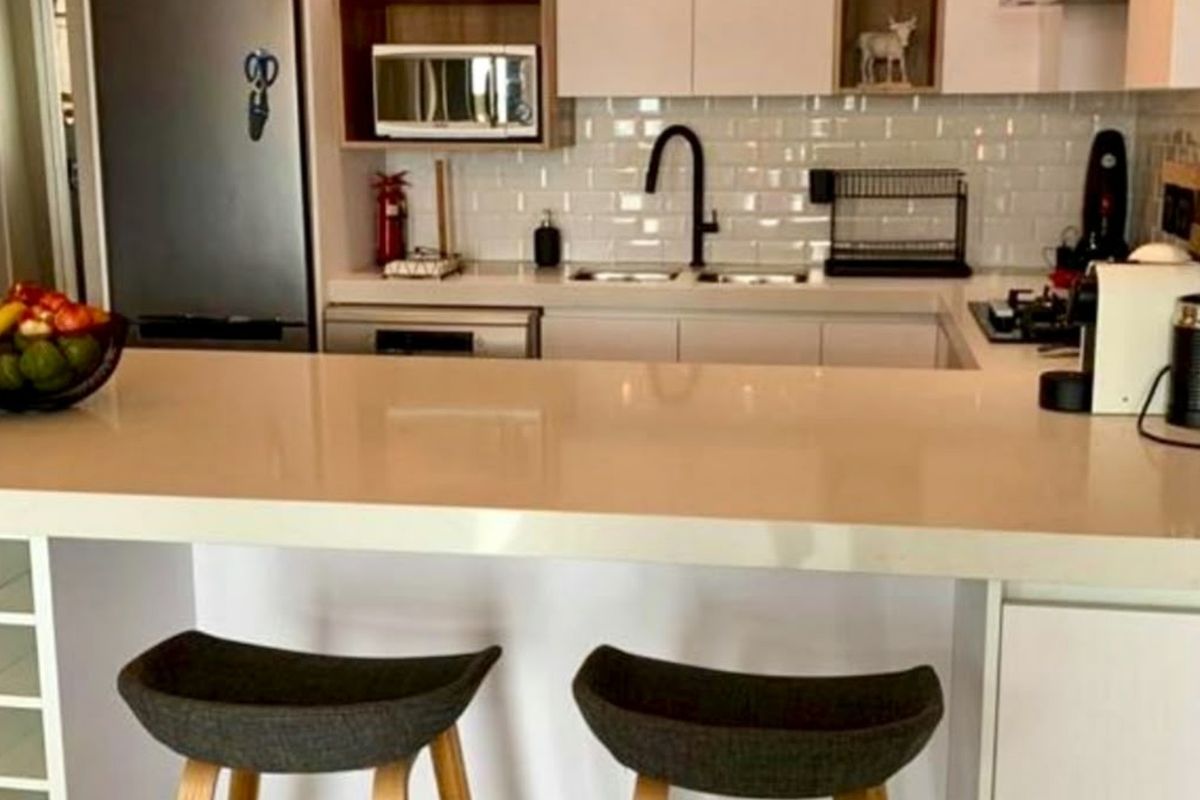 Modern kitchen featuring white cabinetry, quartz countertops, a subway tile backsplash, and a functional breakfast bar for casual dining.