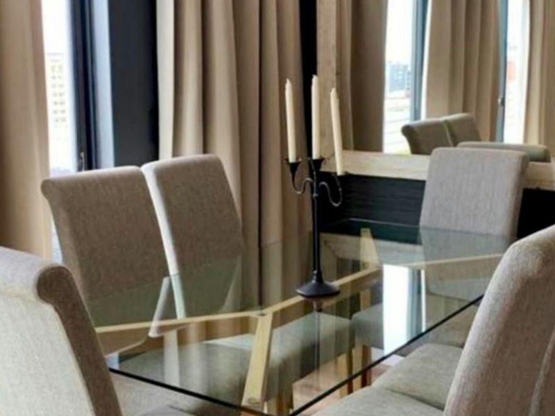 A well-appointed dining area featuring full-height curtains and a large built-in mirror, creating a bright and sophisticated atmosphere.