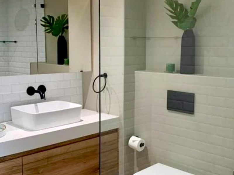 Modern bathroom featuring a wall-mounted basin with matte black fixtures, subway tile detailing, and a sleek wall-hung toilet with a concealed cistern.