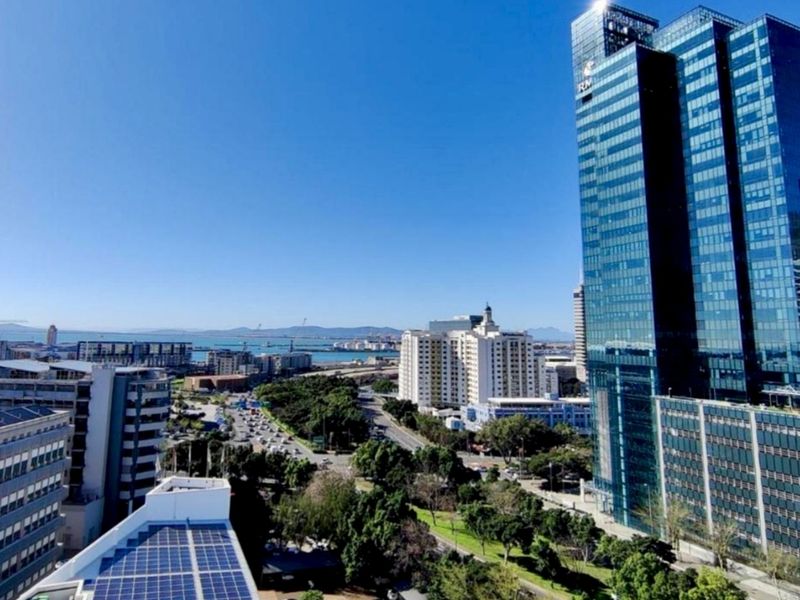 Elevated urban view overlooking the city skyline, surrounding commercial buildings, and distant coastal landscape.