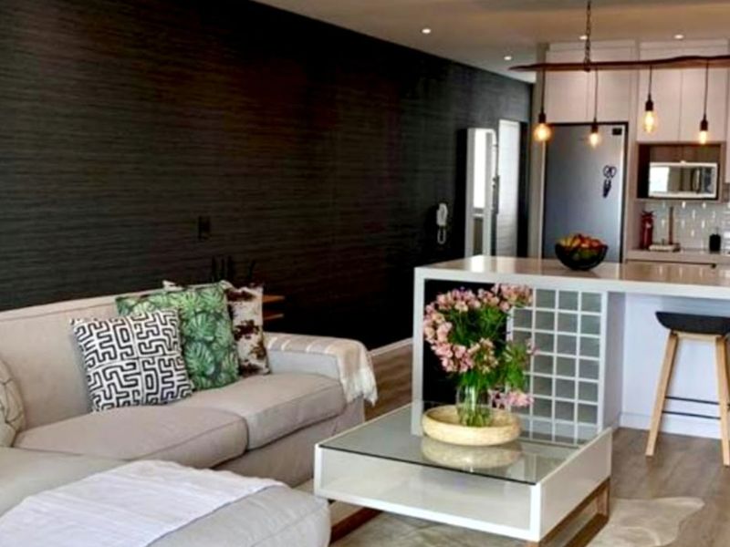 Modern open-plan living area featuring a sleek kitchen with a central island, subway tile backsplash, and contemporary pendant lighting, seamlessly connected to the living space.