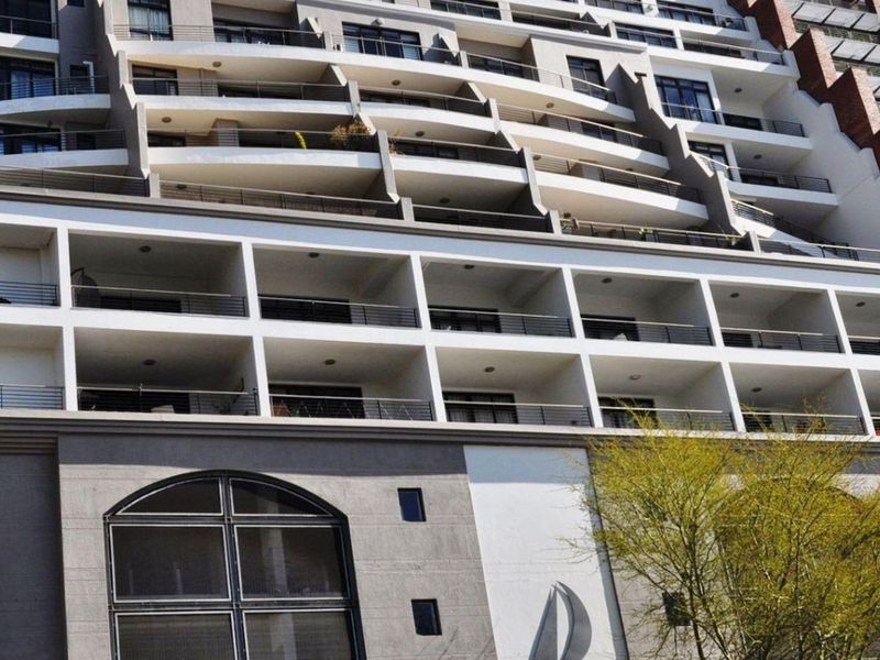 A multi-story apartment building facade featuring tiered balconies with metal railings and modern architectural detailing.