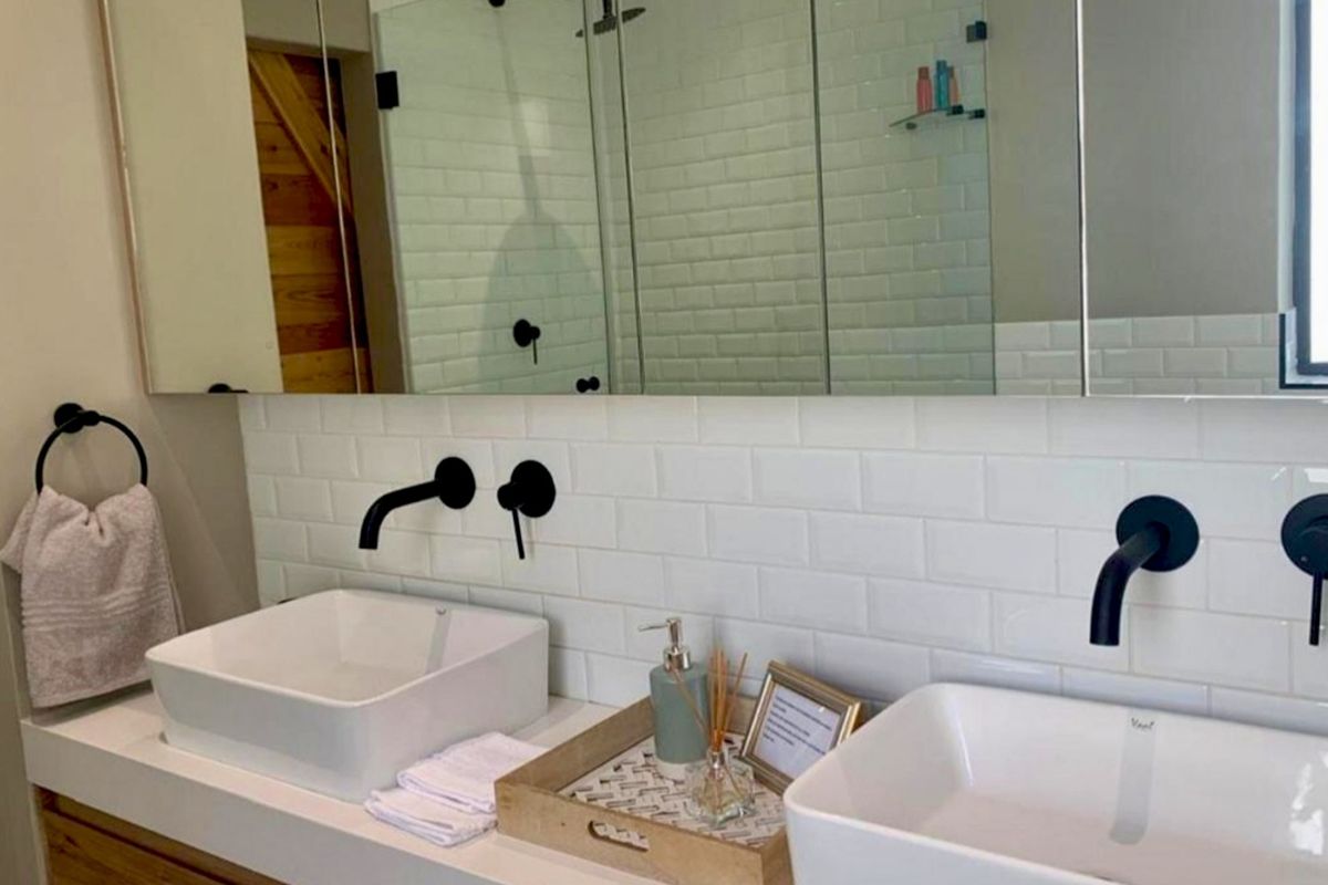 Modern bathroom featuring a double vanity with vessel sinks, wall-mounted matte black faucets, and a clean white subway tile backsplash.