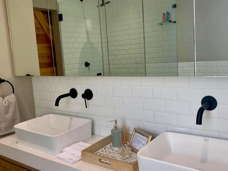 Modern bathroom featuring a double vanity with vessel sinks, wall-mounted matte black faucets, and a clean white subway tile backsplash.