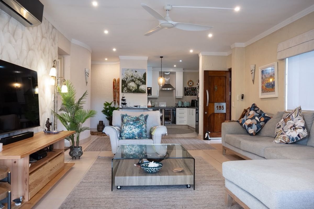 Spacious open-plan living area featuring tiled floors, recessed lighting, a ceiling fan, and a seamless transition to a modern kitchen with built-in cabinetry.