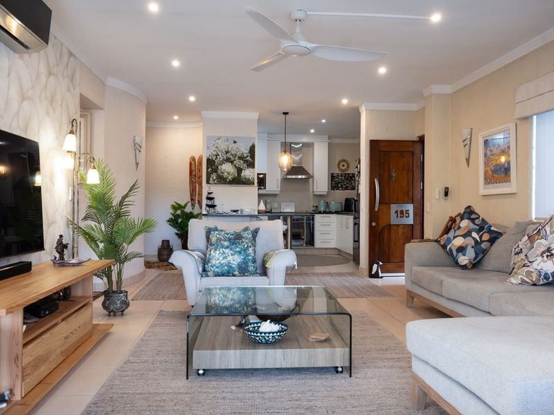 Spacious open-plan living area featuring tiled floors, recessed lighting, a ceiling fan, and a seamless transition to a modern kitchen with built-in cabinetry.