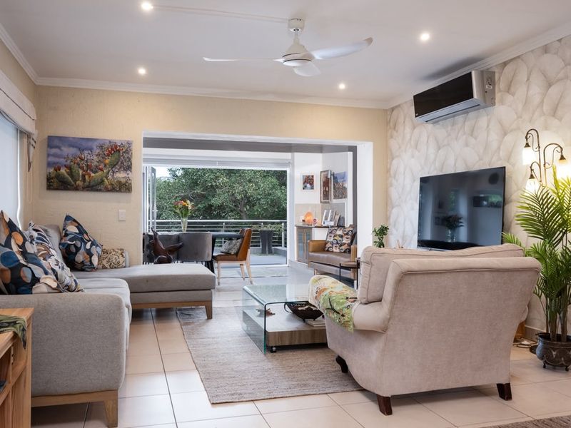 Spacious living room featuring tiled flooring, recessed lighting, a ceiling fan, and a split-system air conditioner, with seamless access to an outdoor patio area.