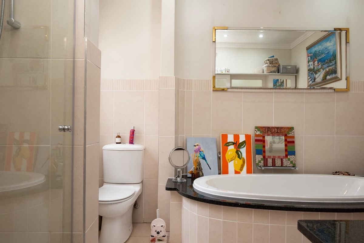 A well-maintained bathroom featuring a built-in bathtub with a granite surround, a separate shower enclosure, and neutral wall tiling.