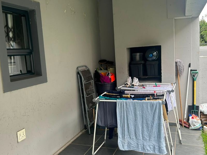Covered patio area featuring a built-in braai and tiled flooring, providing a functional outdoor space for entertainment.