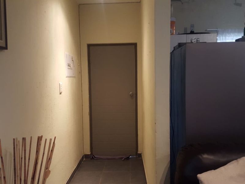 A simple interior hallway featuring tiled flooring and a neutral wall finish, providing access to adjacent living areas.