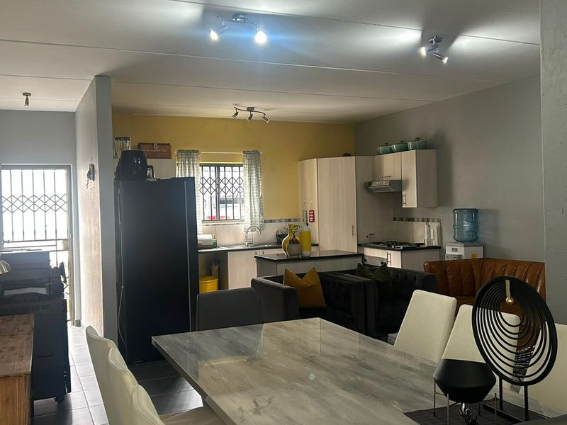 Open-plan living and kitchen area featuring tiled floors, built-in cabinetry, and direct access to a secure entrance.