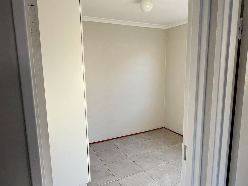 A vacant bedroom featuring neutral wall finishes, tiled flooring, and a built-in cupboard, awaiting final touches like skirting boards.