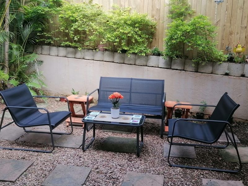 A private garden area featuring a retaining wall, timber fencing, and stone pavers set within a gravel landscape.