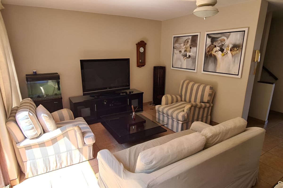 A comfortable living room featuring tiled flooring, a ceiling fan, and a sliding glass door providing access to the outdoor area.