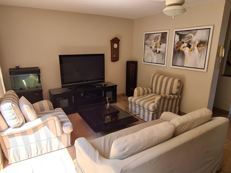 A comfortable living room featuring tiled flooring, a ceiling fan, and a sliding glass door providing access to the outdoor area.