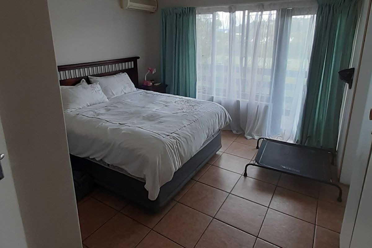 A bedroom featuring tiled flooring, a wall-mounted air conditioning unit, and a sliding glass door providing access to the exterior.