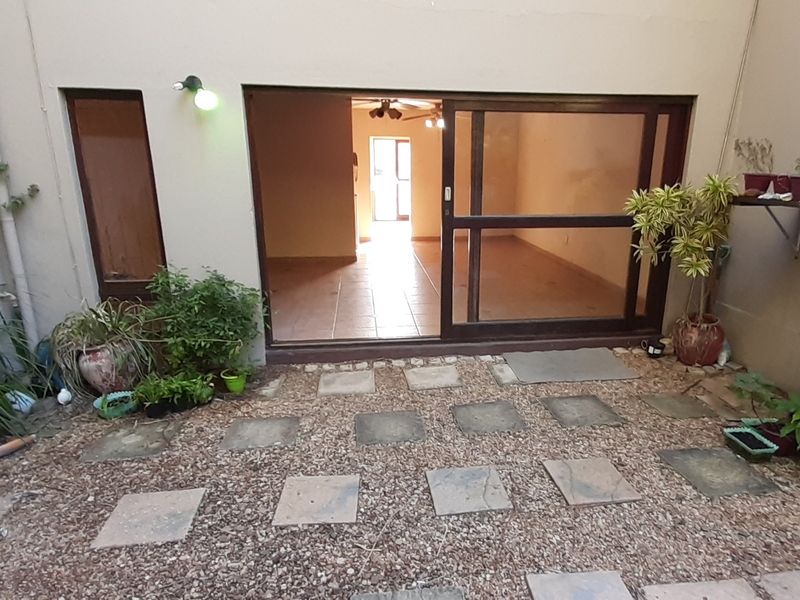 A rear courtyard area featuring a gravel base with paved stepping stones and a large sliding glass door providing access to the interior living space.