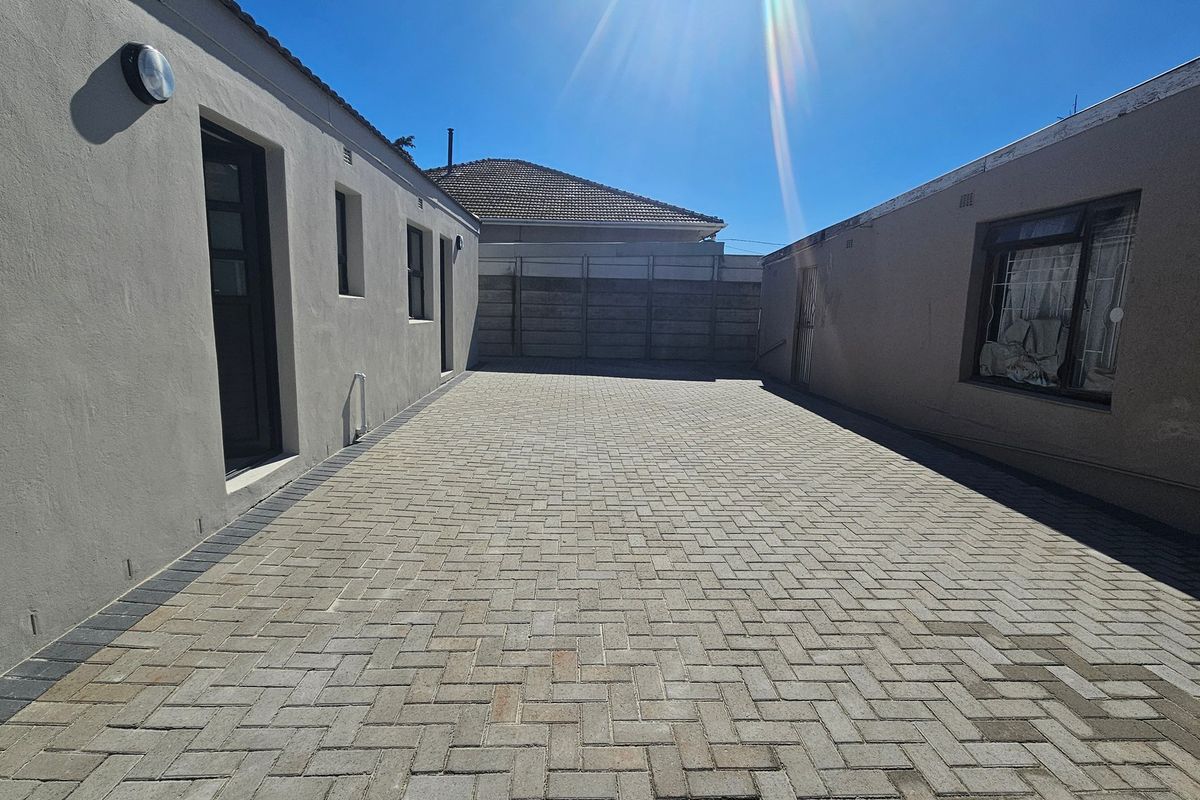 A paved rear courtyard area featuring concrete boundary walls and exterior lighting, providing a clean and functional outdoor space.