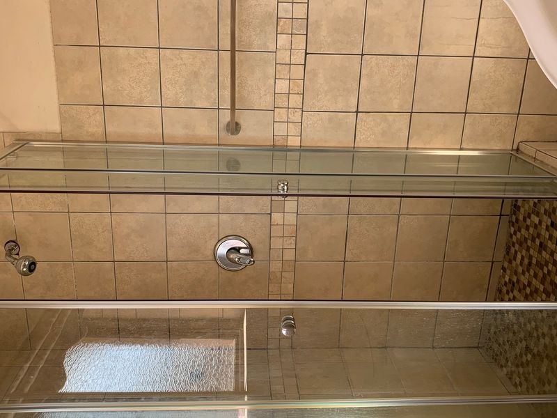 A functional shower area featuring a glass enclosure, tiled walls with mosaic accents, and a standard shower mixer.