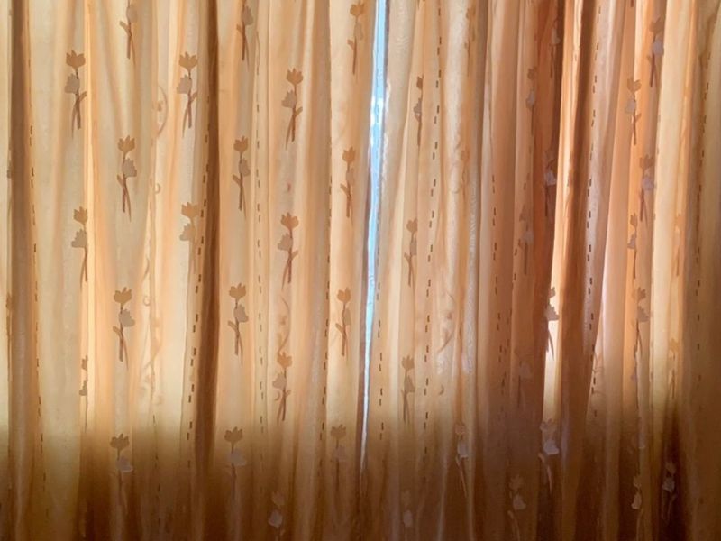 A close-up view of window curtains covering a window, providing no architectural information about the room.