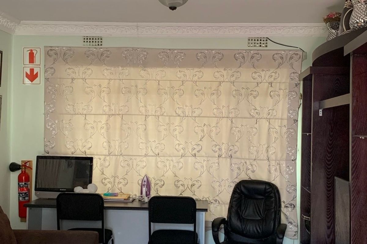 A living area featuring decorative ceiling cornicing, wall-mounted ventilation grilles, and a fire safety station.