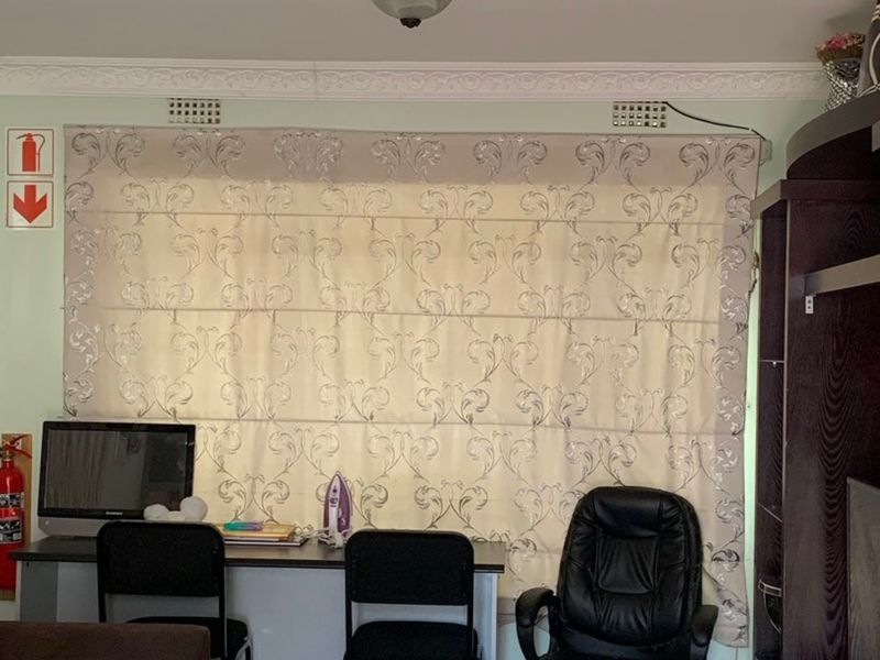 A living area featuring decorative ceiling cornicing, wall-mounted ventilation grilles, and a fire safety station.