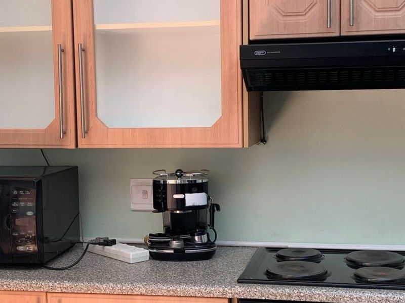 A functional kitchen area featuring laminate cabinetry, a granite countertop, an electric hob, and a built-in extractor fan.