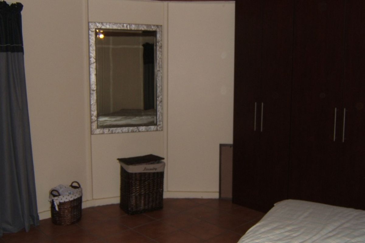 A bedroom featuring dark wood built-in cupboards and tiled flooring, providing functional storage space within the room.