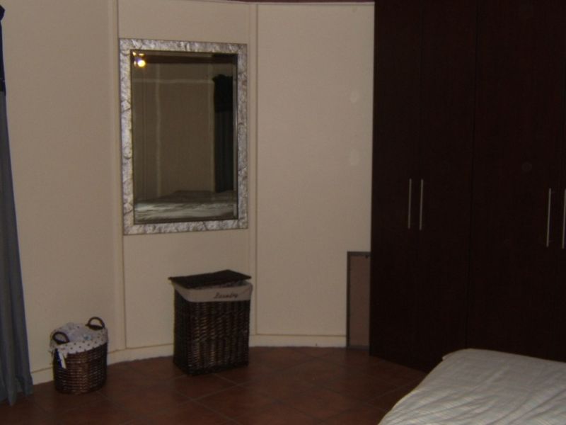 A bedroom featuring dark wood built-in cupboards and tiled flooring, providing functional storage space within the room.