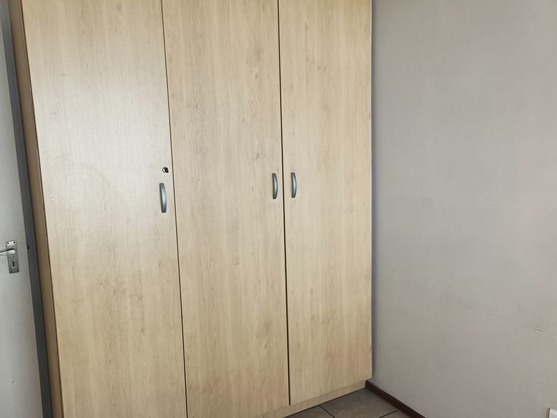 A bedroom featuring a light wood-finish built-in wardrobe and tiled flooring.