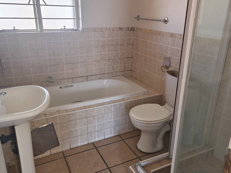 A dated bathroom featuring a bathtub, separate shower enclosure, pedestal basin, and toilet with neutral tiled finishes throughout.