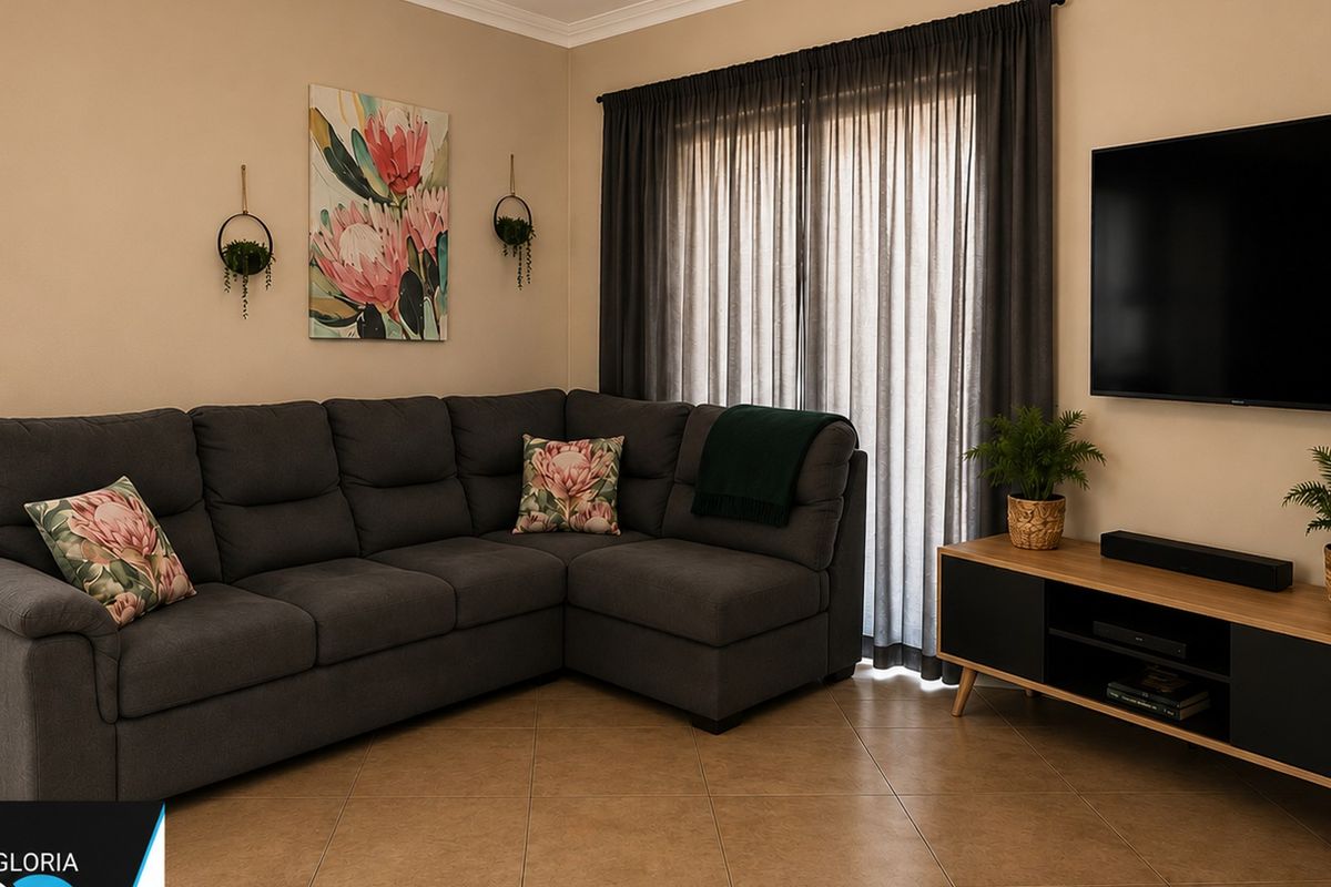 A well-maintained living room featuring neutral wall tones, tiled flooring, and large window treatments, creating a comfortable and inviting space.