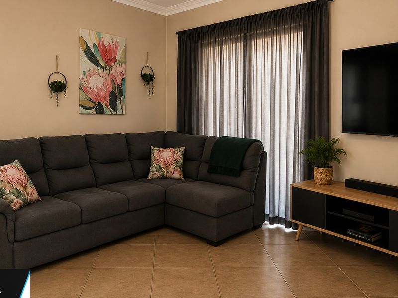 A well-maintained living room featuring neutral wall tones, tiled flooring, and large window treatments, creating a comfortable and inviting space.