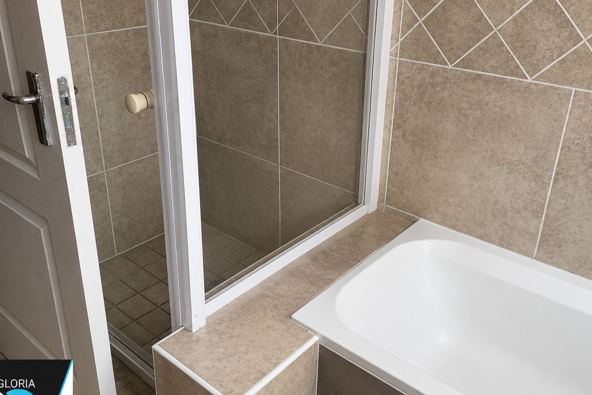 A clean bathroom featuring a built-in bathtub and a separate shower enclosure with neutral tiled finishes.