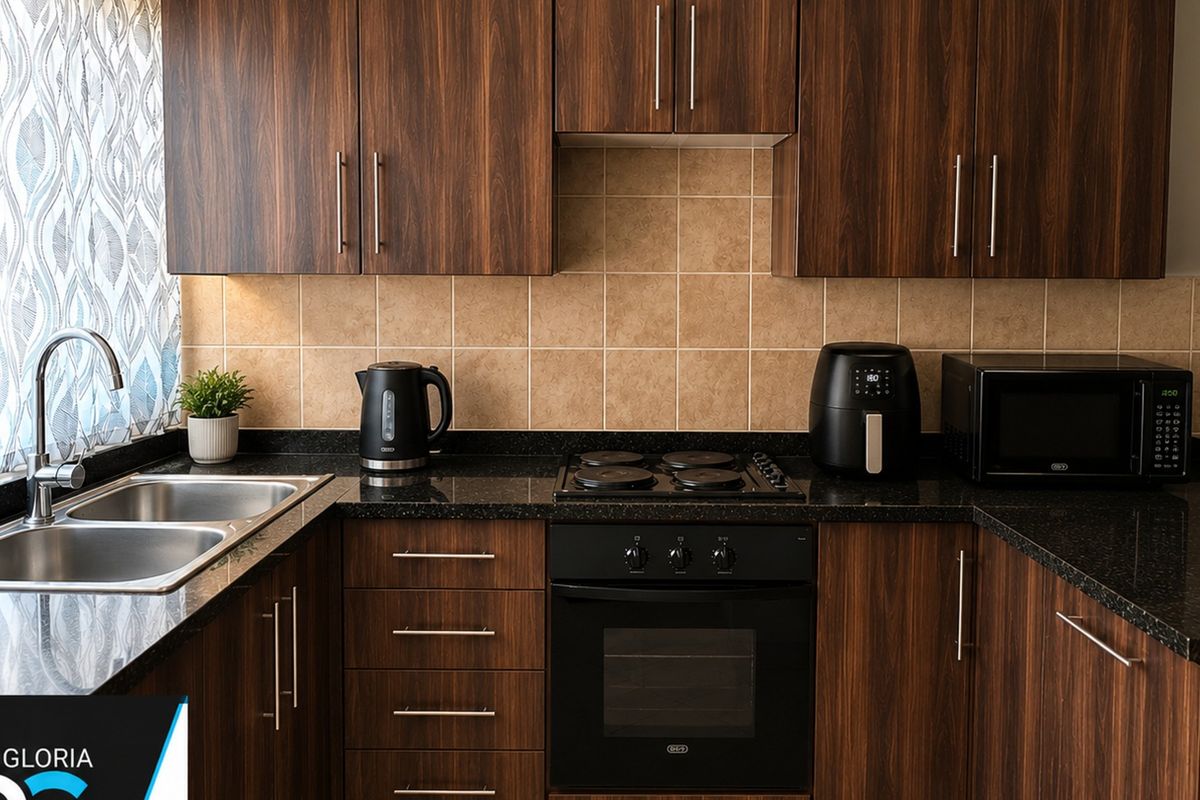 A well-maintained kitchen featuring dark wood cabinetry, granite countertops, a double bowl stainless steel sink, and integrated oven with electric hob.