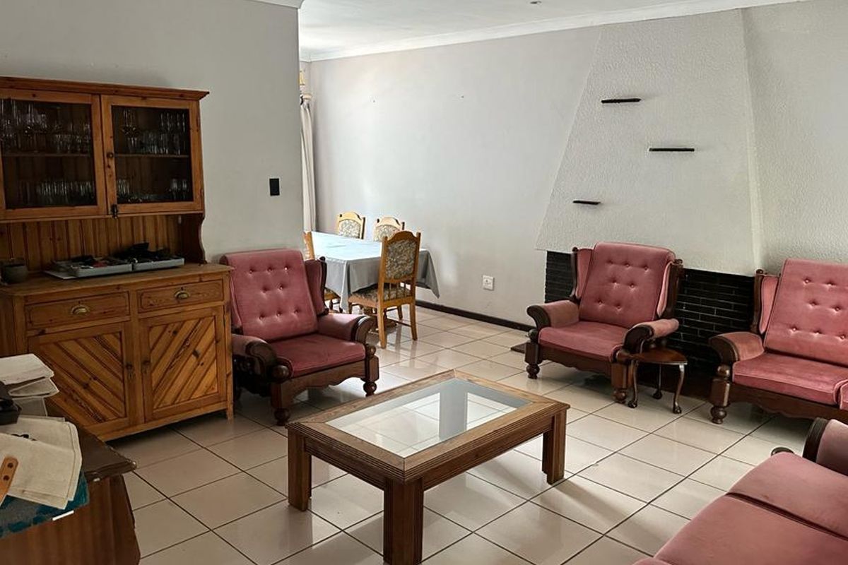 Spacious living area featuring neutral tiled flooring and a prominent built-in fireplace, offering a functional layout for comfortable family living.