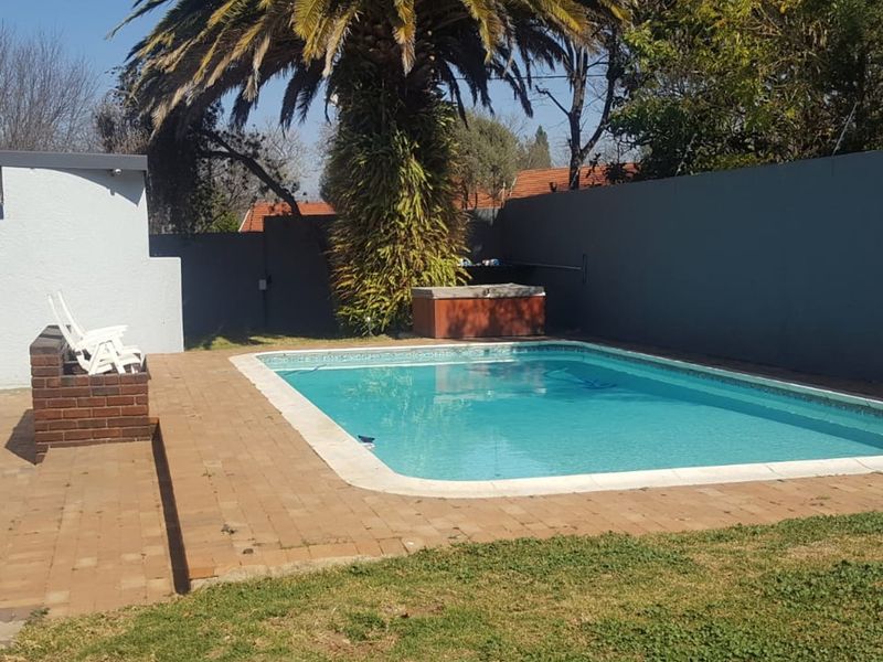 Outdoor pool area featuring a swimming pool, brick paved patio, and perimeter boundary wall, providing a private space for recreation.