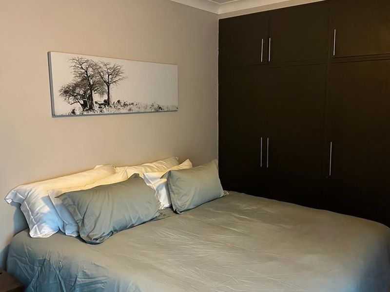 A well-maintained bedroom featuring dark built-in cupboards and neutral wall finishes.
