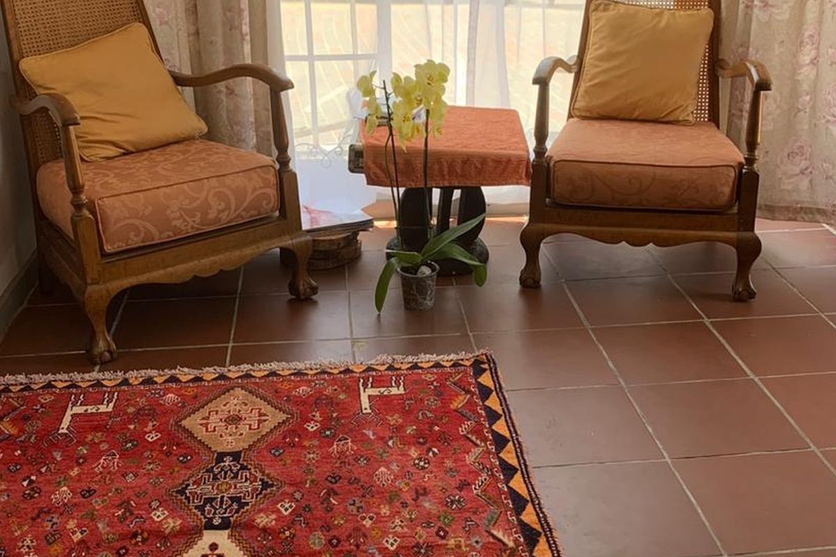 A cozy living area featuring traditional terracotta floor tiles and large french doors that provide natural light.