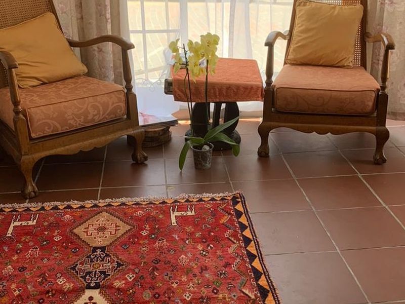 A cozy living area featuring traditional terracotta floor tiles and large french doors that provide natural light.