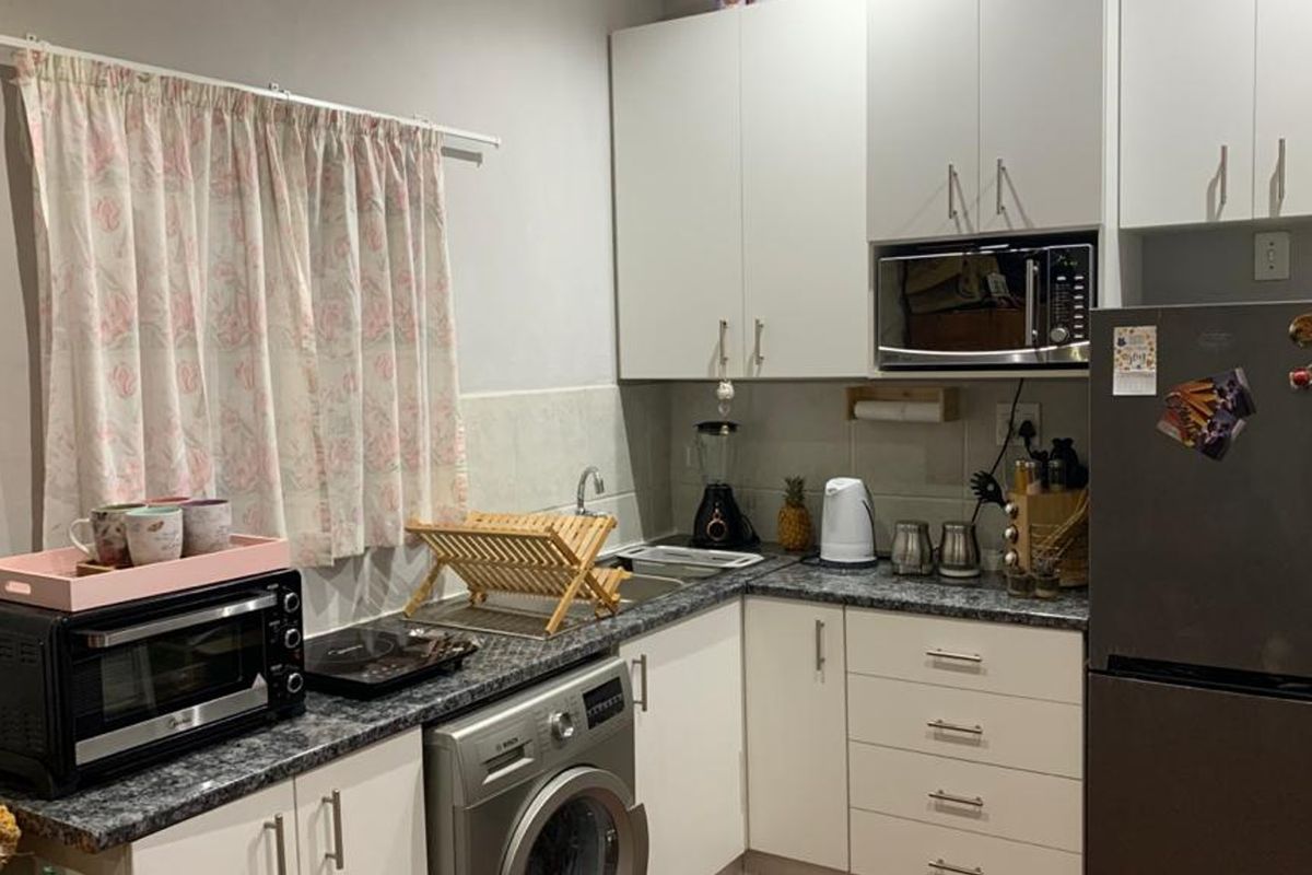 Compact kitchen featuring white cabinetry, laminate countertops, a stainless steel sink, and a built-in microwave with space for a washing machine.