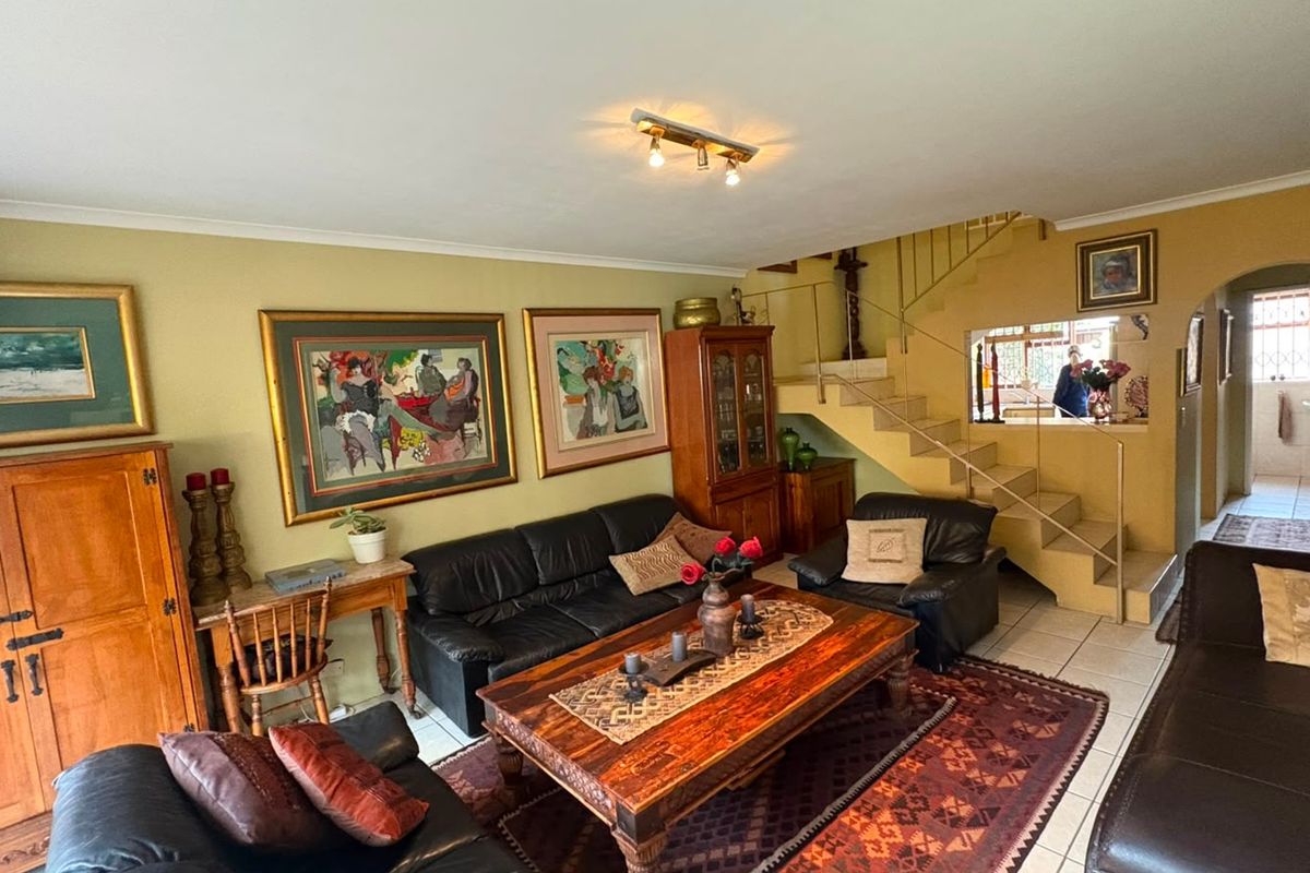 Spacious living room featuring tiled flooring, a central staircase, and an archway leading to the rear of the property.