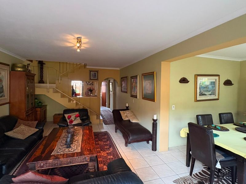 Open-plan living and dining area featuring tiled flooring, a central staircase, and an arched entryway leading to the rest of the home.