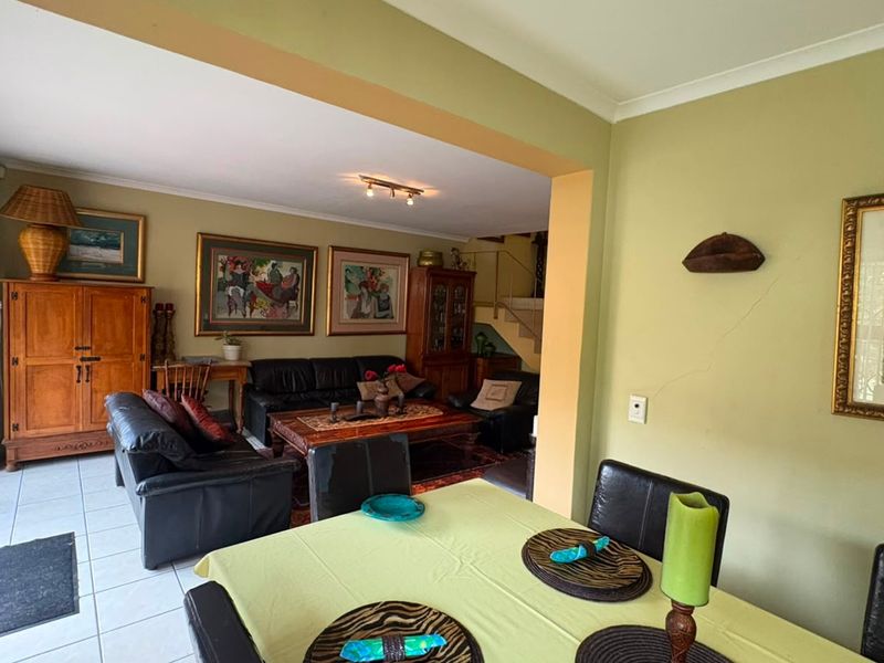 Open-plan living and dining area featuring tiled flooring, track lighting, and access to the exterior through a sliding glass door.
