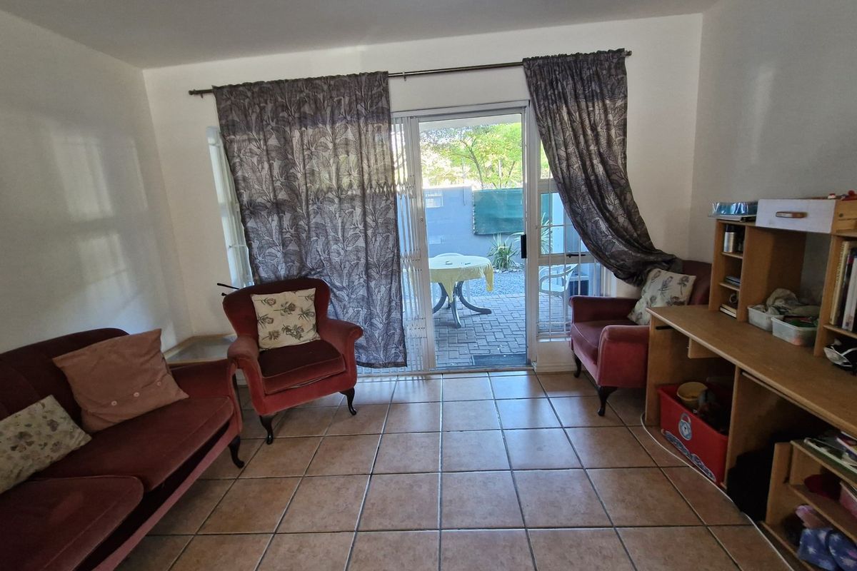 A living room featuring tiled flooring and a sliding glass door providing direct access to an outdoor patio area.