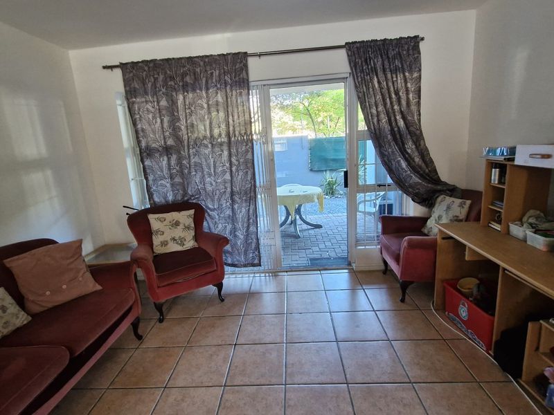 A living room featuring tiled flooring and a sliding glass door providing direct access to an outdoor patio area.
