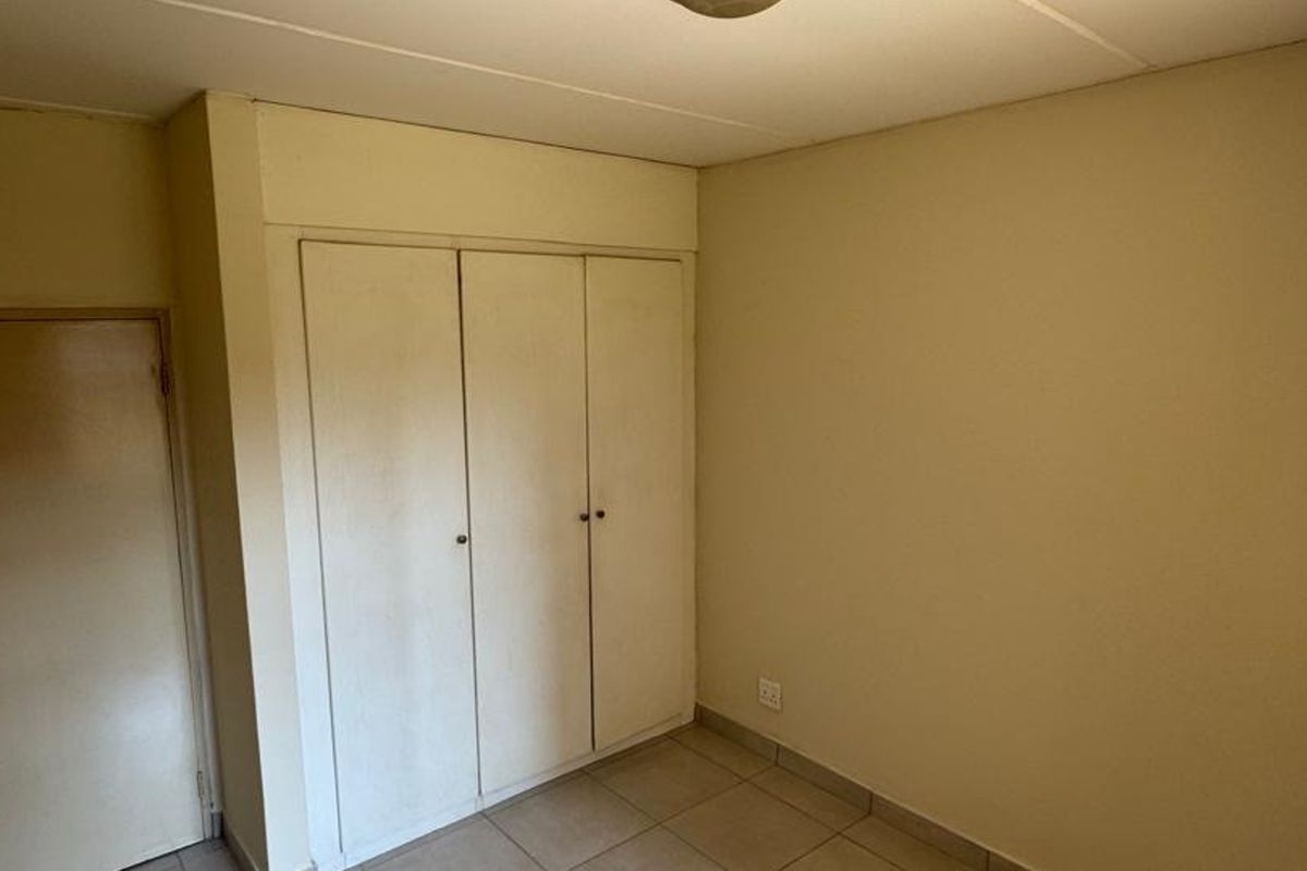 An empty bedroom featuring tiled flooring and built-in cupboards, offering a blank canvas for personalization and interior design updates.