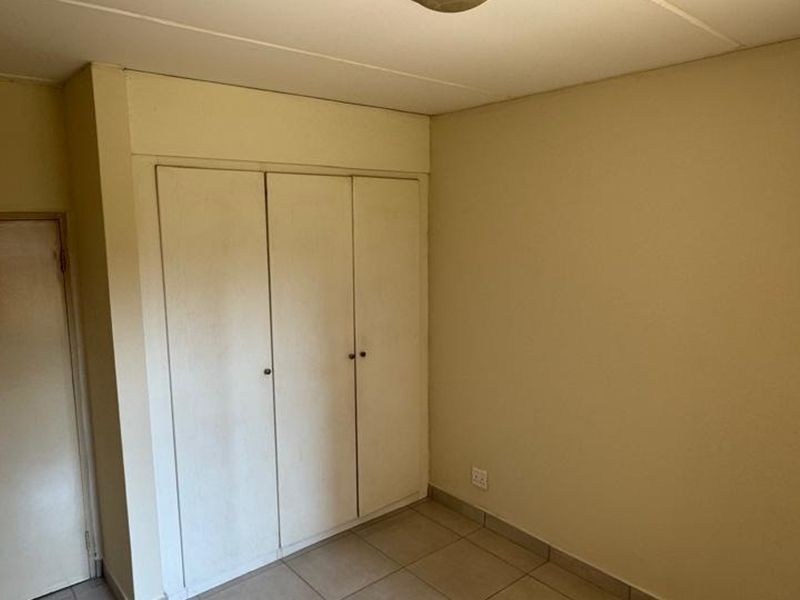 An empty bedroom featuring tiled flooring and built-in cupboards, offering a blank canvas for personalization and interior design updates.
