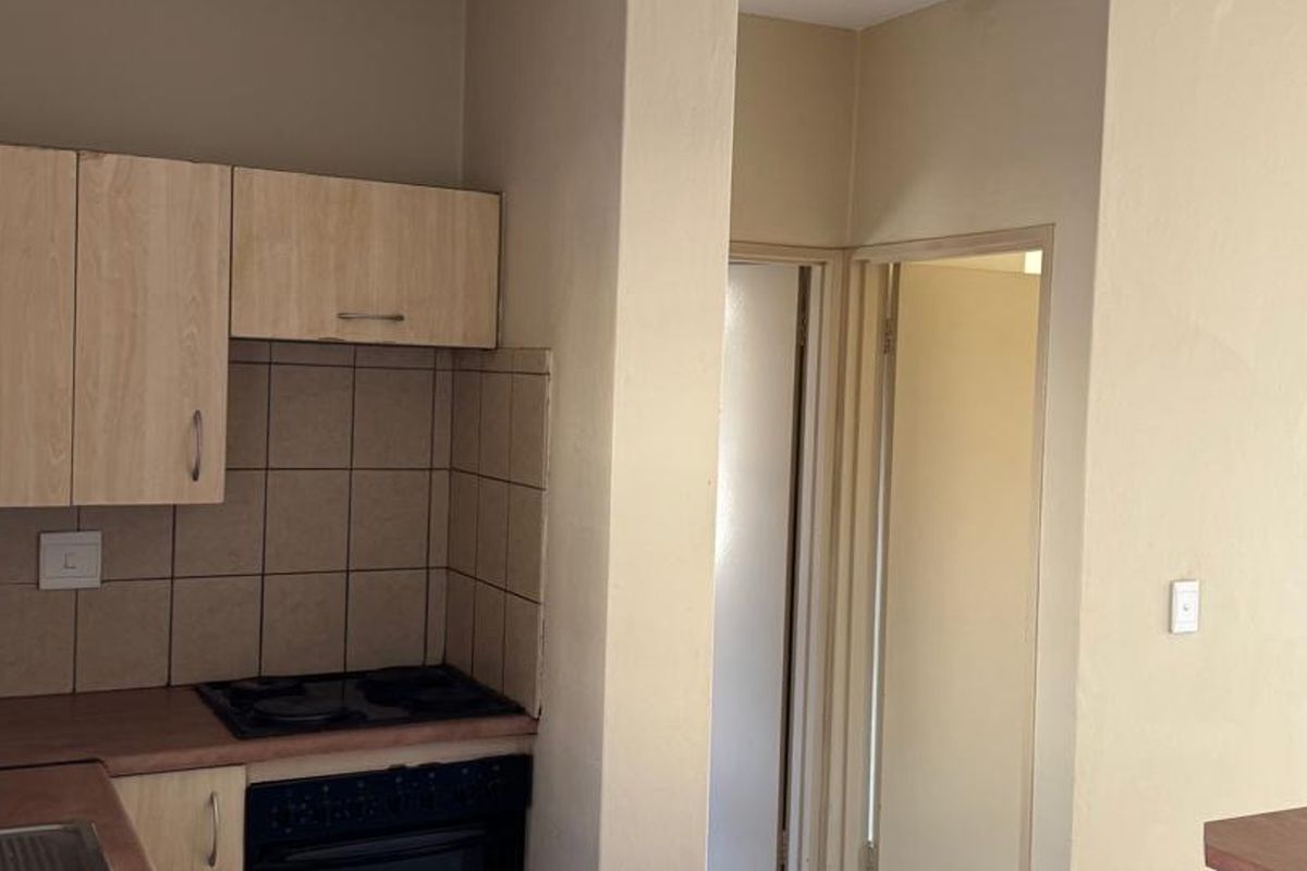 A functional kitchen area featuring built-in cabinetry, a tiled backsplash, and integrated cooking appliances, providing a practical layout for daily use.