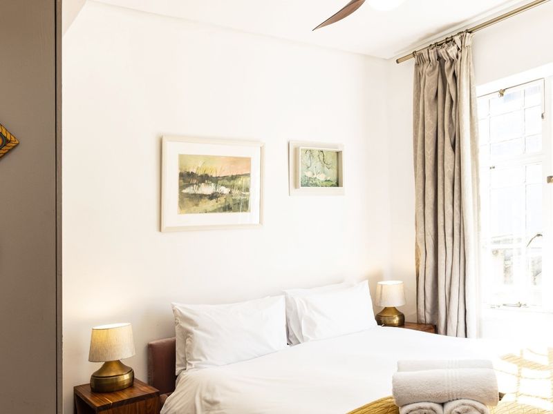 A well-lit bedroom featuring a window with curtain rod and a ceiling fan, providing a comfortable and functional living space.